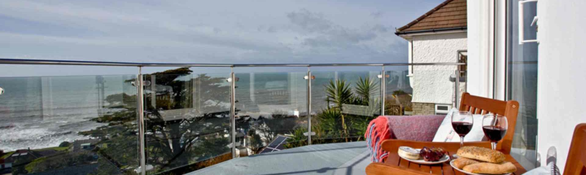 Outdoor  furniture on a glass-fronted balcony offers beach views on the Cornish coast at Downderry