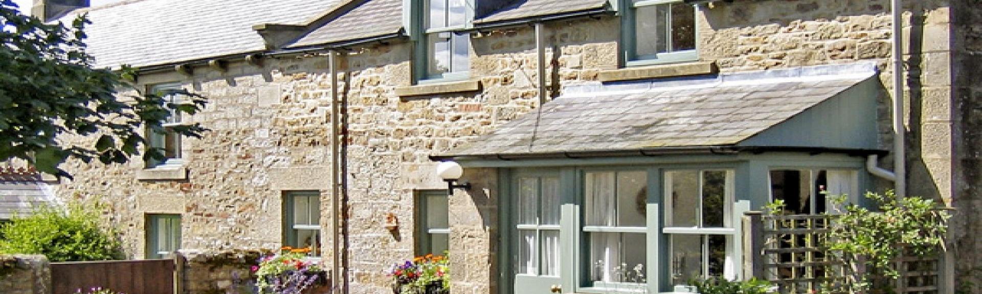 Exterior of a 2-storey stone-built Northumberland cottage.
