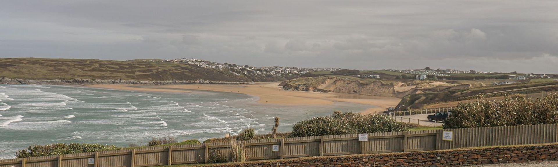 A Cornish landscape view looking across open fields, sand dunes to the sandy surfing beach at Crantock