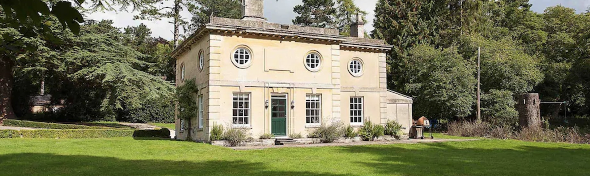 A period honeystone estate house with large windows overlooks fields and woodlands