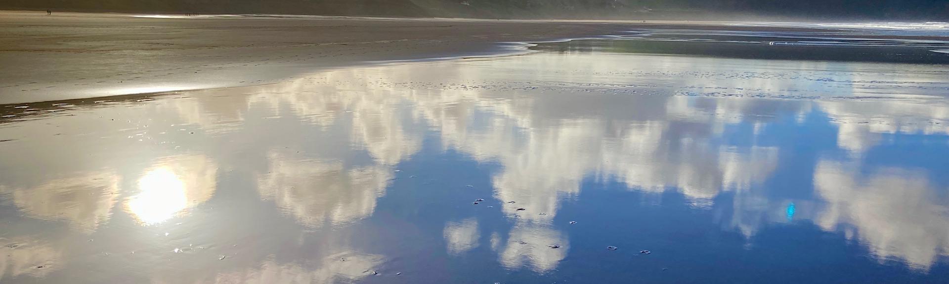 A mirror reflection of blue sky and clouds in the wet sand on Woolacombebeach
