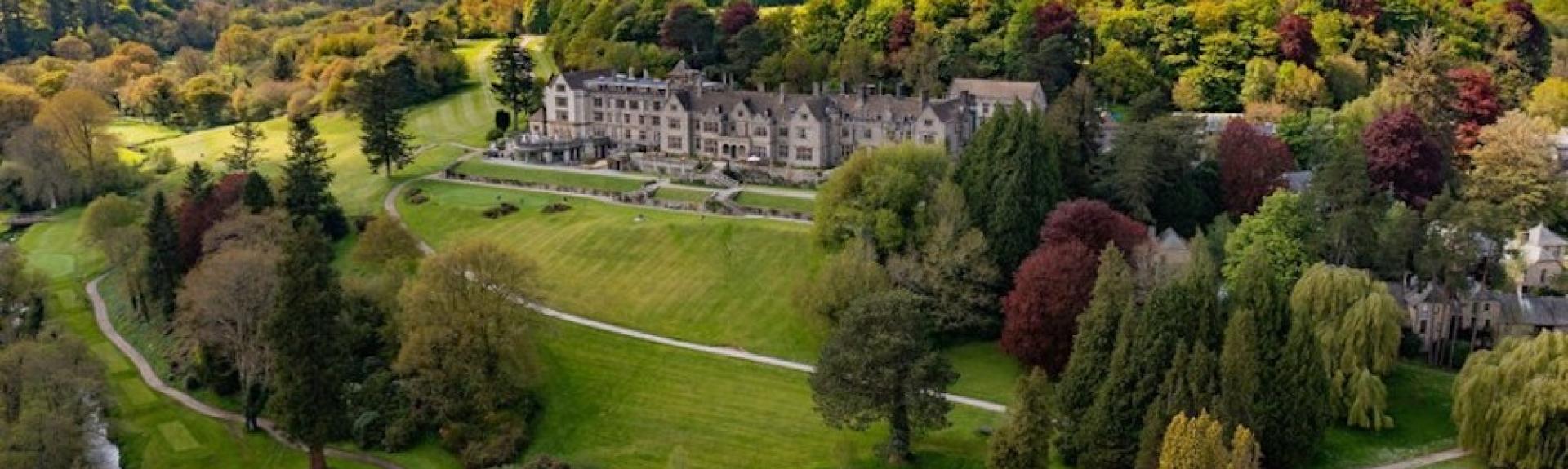 Aerial view of a large country house hotel in Devon surrounded by woods and fields on the edge of Datrmoor.