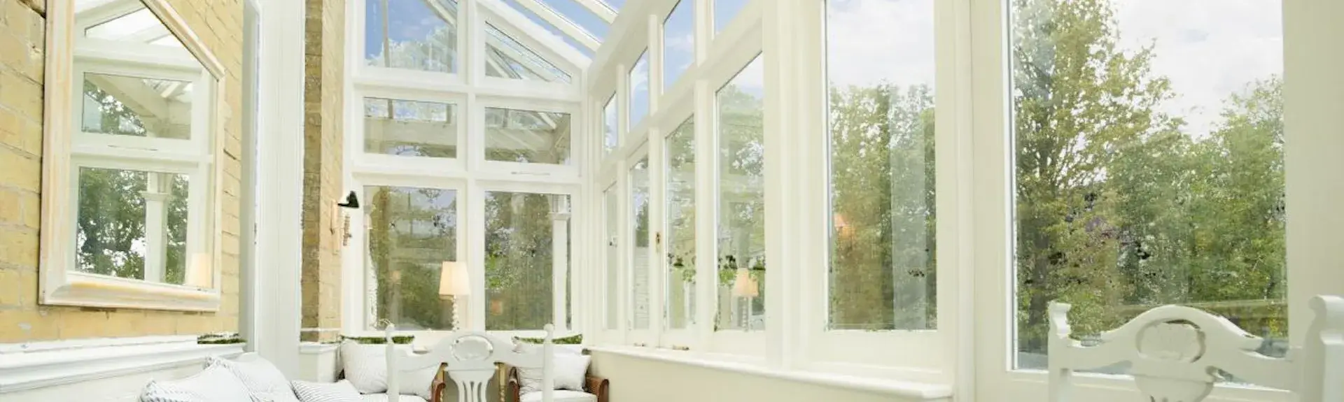  long conservatory with a large dining table, wrought iron chairs and a sofa