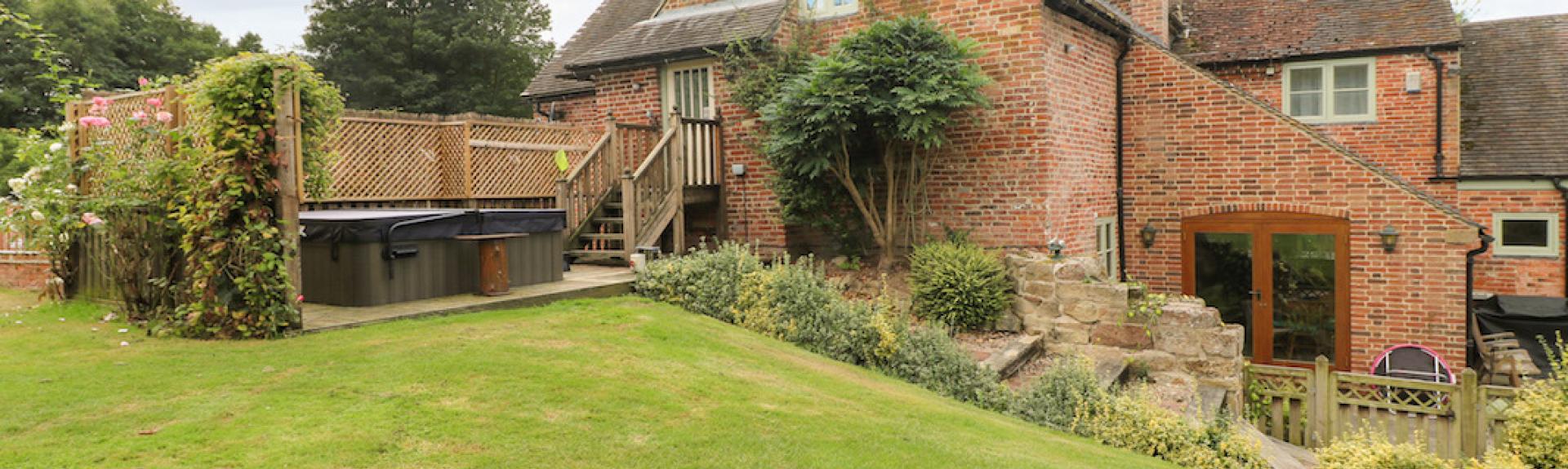 A brick-built, 3-storey holiday cottage with a hot tub and large lawn.