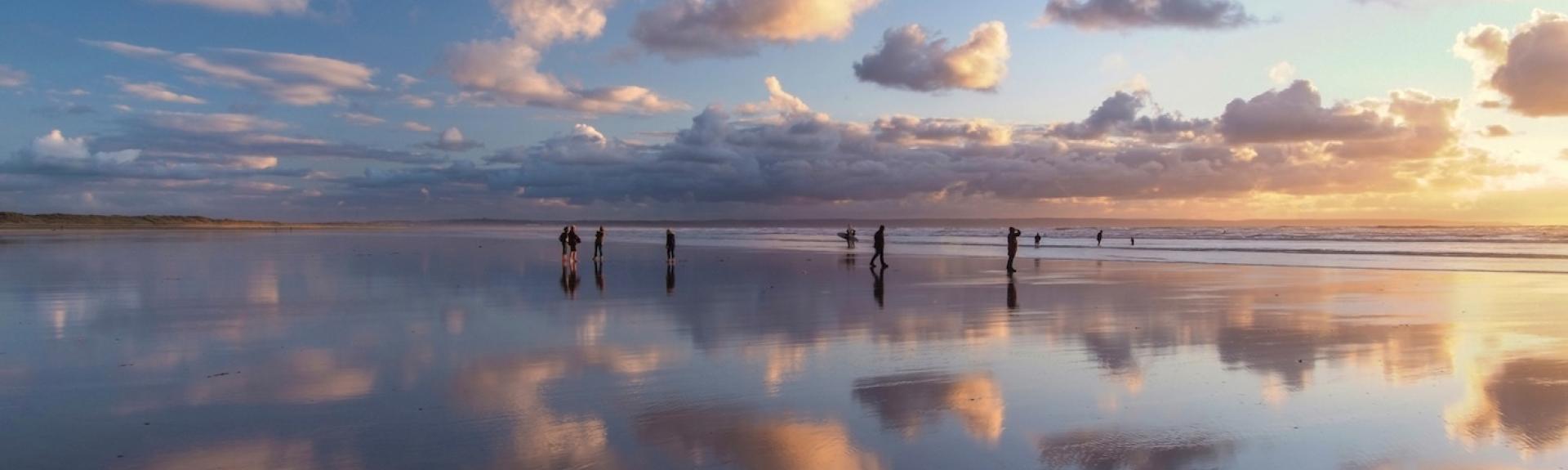 Small clouds are reflected in the wet surface of a sandy beach in North Devon.