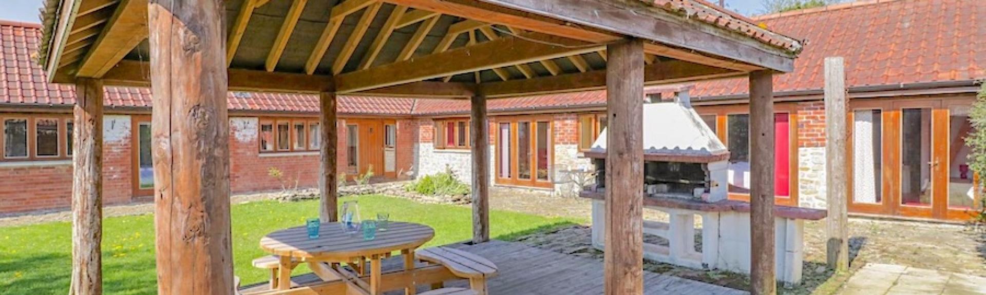 A covered bbq area in a garden of a barn conversion.