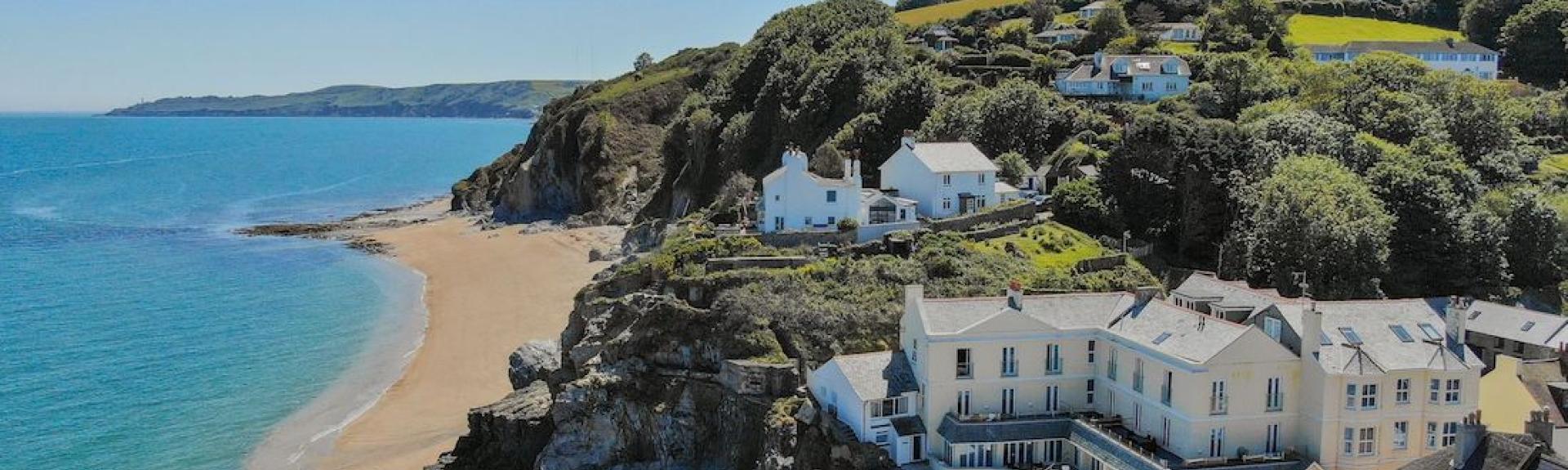 Cottages on a promenade look over a sandy South Devon beach.