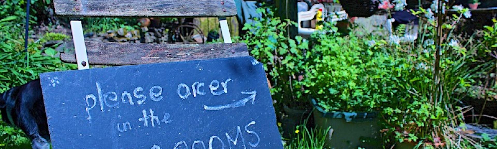 A blackboard sign  perched on a wooden chair welcoming customers to an Exmoor Tearoom