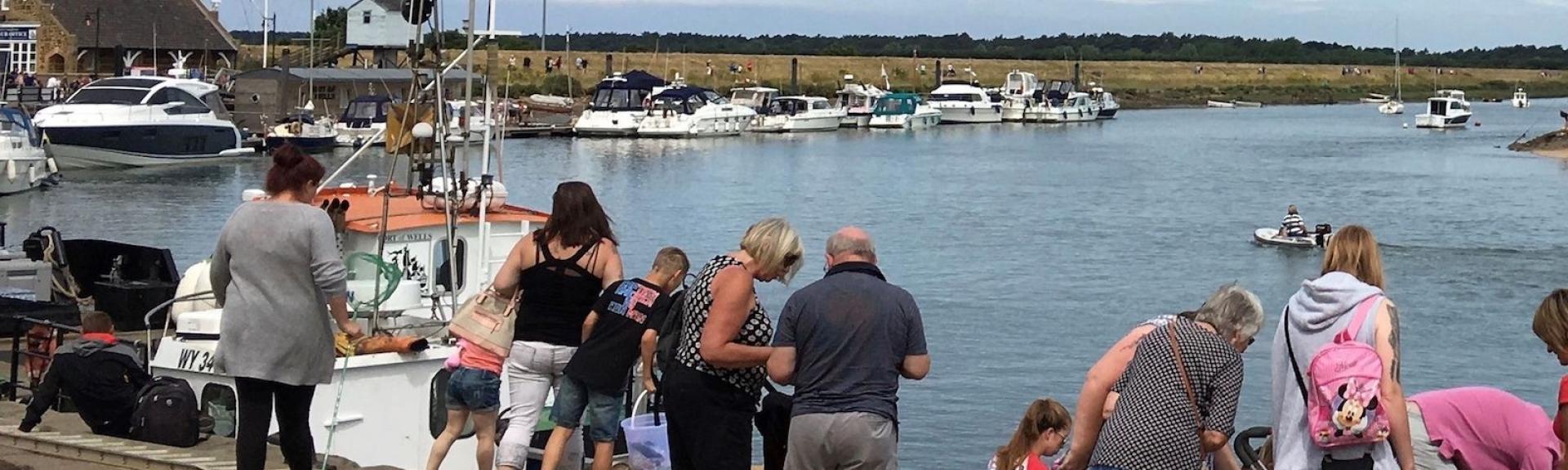 Families crabbing on a quayside at high tide