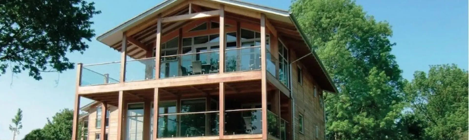 A large holiday lodge in a rural setting with an oak framework and large glass windows=