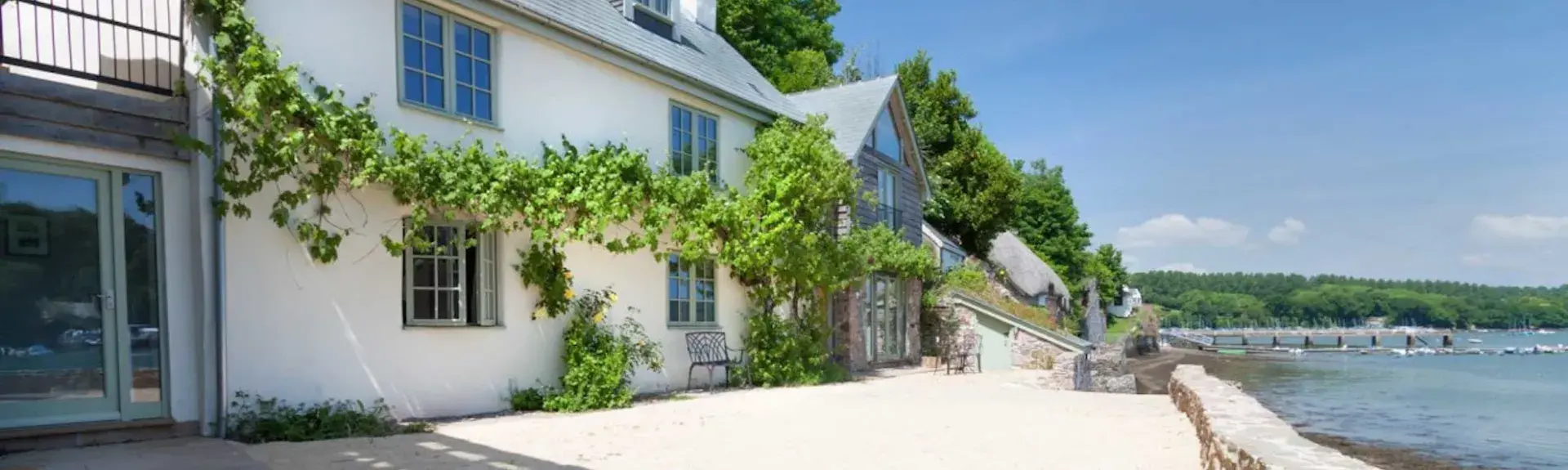 A Waterside, restored, wisteria-clad fisherman's cottage overlooks the Dart Estuary at high tide.