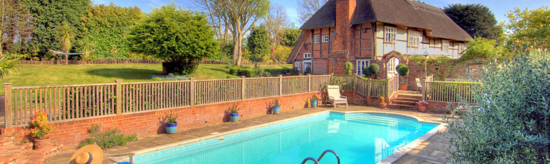 An open air swimming pool surrounded by a wide terrace in Kent on a summer's day