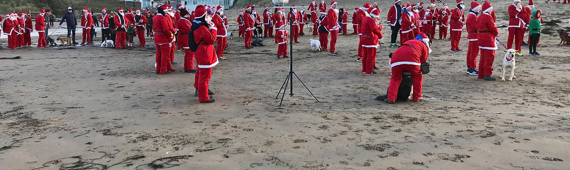 Santa Claus's limber up for the start of a Santa Fun Run on Woolacombe Sands in North Devon