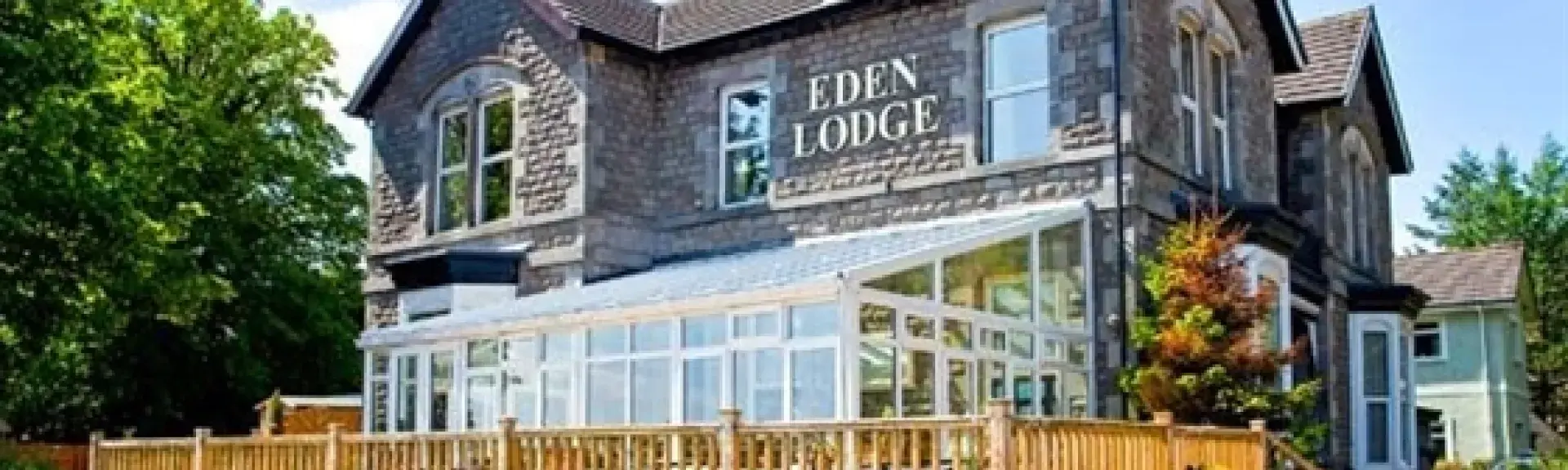 A large 2-storey holiday cottage with an extensive deck overlooks a garden.