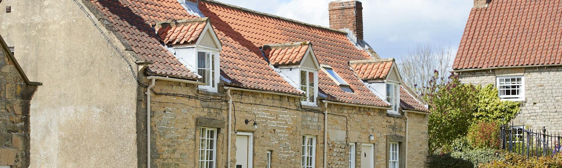 the exterior of a stone built holiday cottage in North Yorkshire with terracotta roof and grassy lawns.