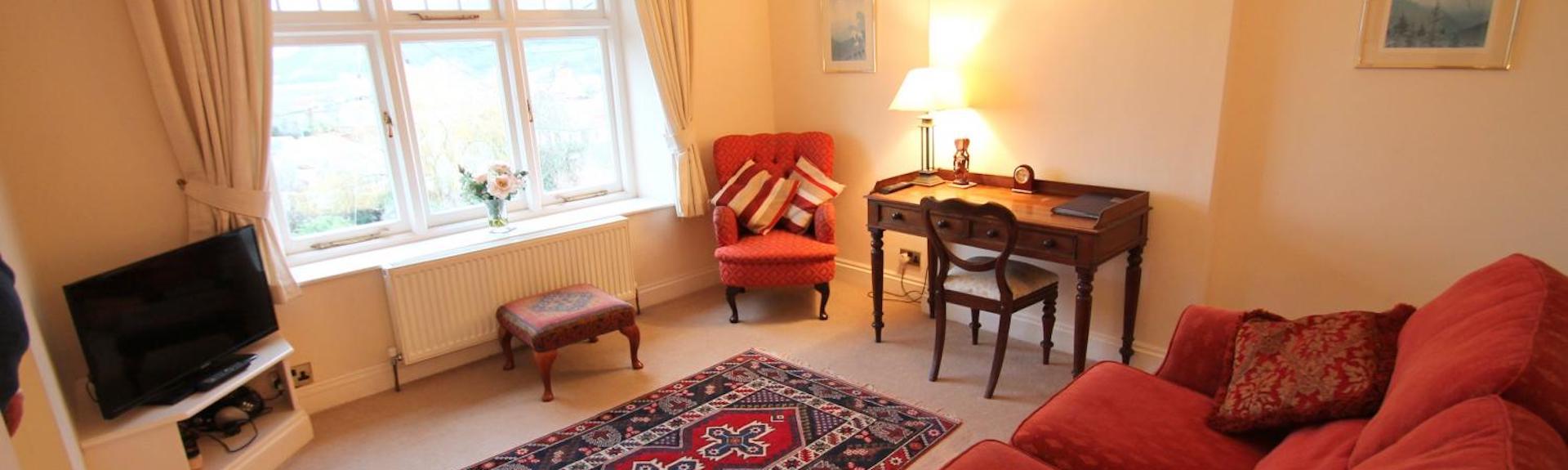A Somerset holiday apartment lounge with comfortable sofa, TV and side tables.