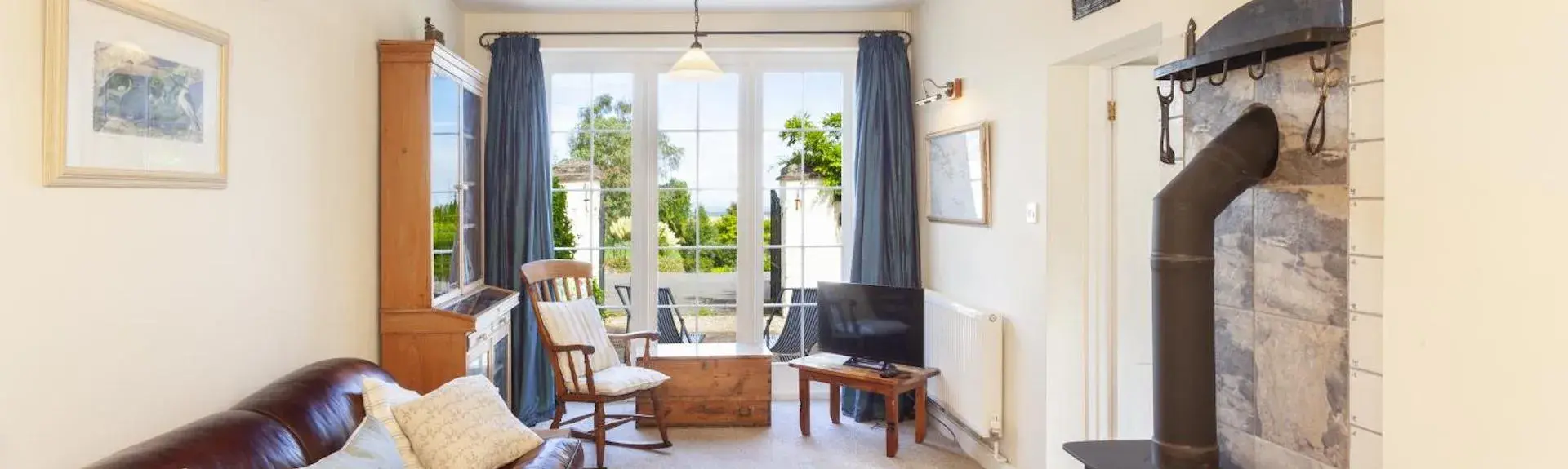 A Exmoor coastal cottage lounge with leather sofas, French windows to a garden.