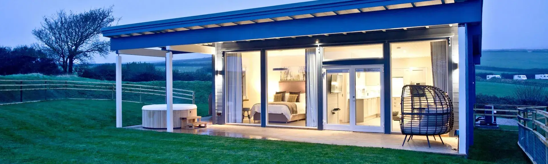 A contemporary glass-fronted eco-lodge with a hot tub and large garden.