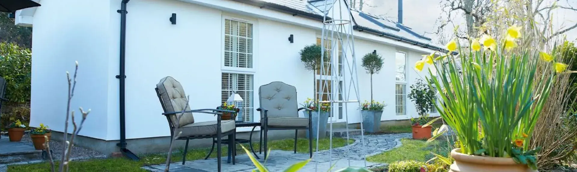 Single storey holiday cottage in Glamorgan with a terrace bordered by a low stone wall.