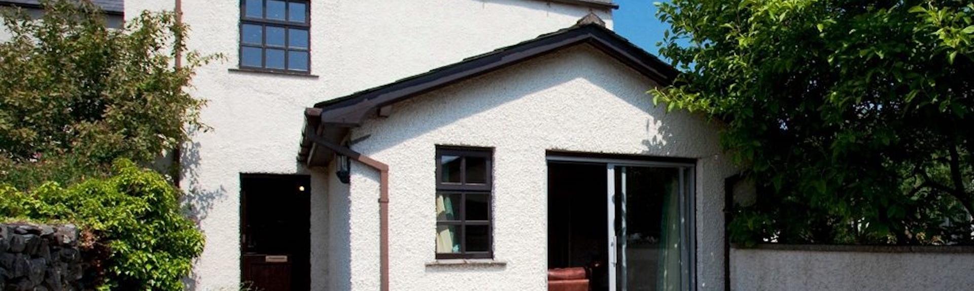 Exterior of a holiday cottage in Cark-in-Cartmell overlooking a small patio and lawn.