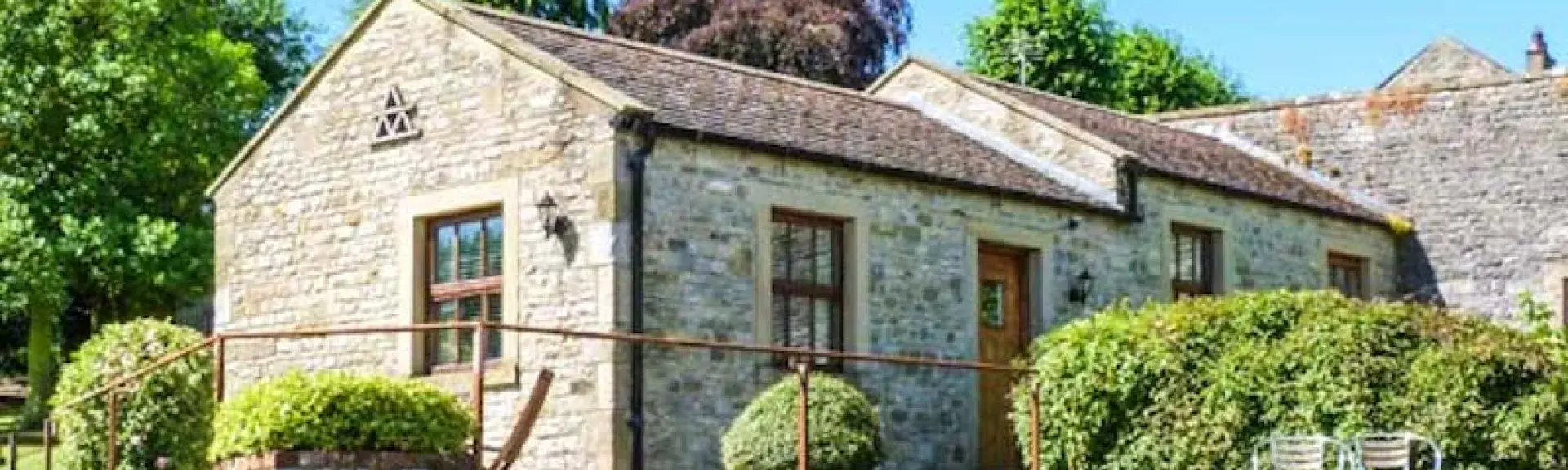 A siungle storey wing of a stone-bult property overlooks a terrace and gardens.
