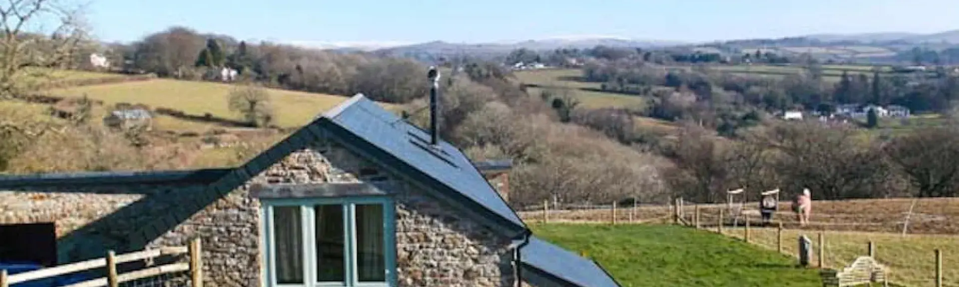 Exterior of a stone-built Dartmoor holiday cottage tucked into a fold in the surrounding Devon countryside