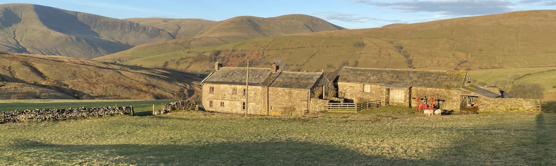 A stone-built Cumbrian farmhouse and attached barns in a remote moorland location