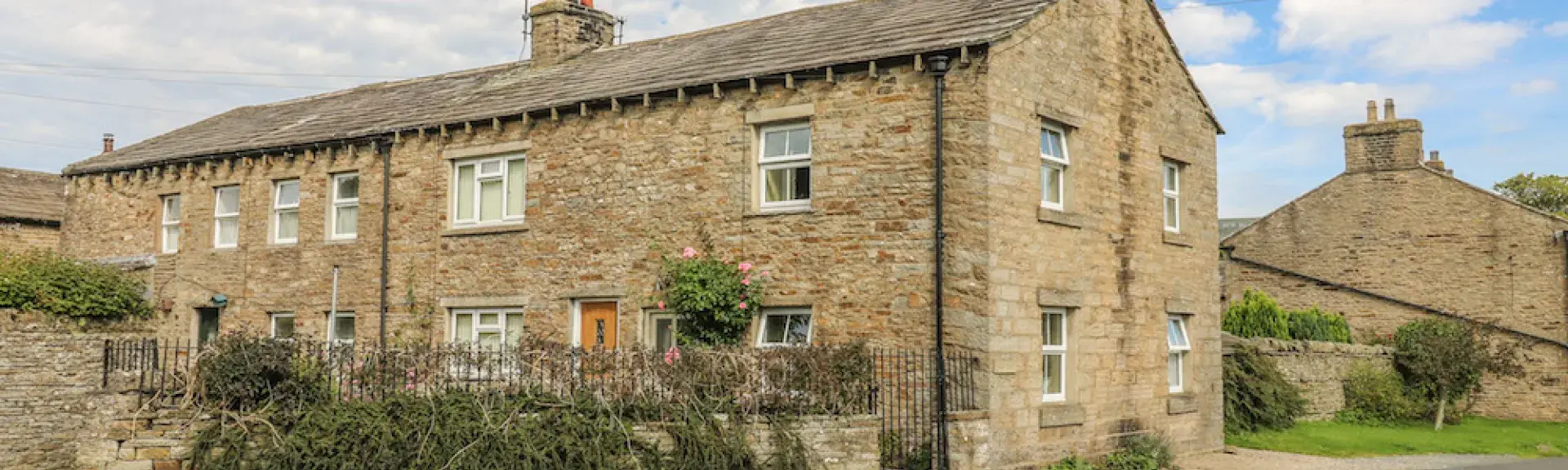 A row of three stone-built cottages with walled gardens.