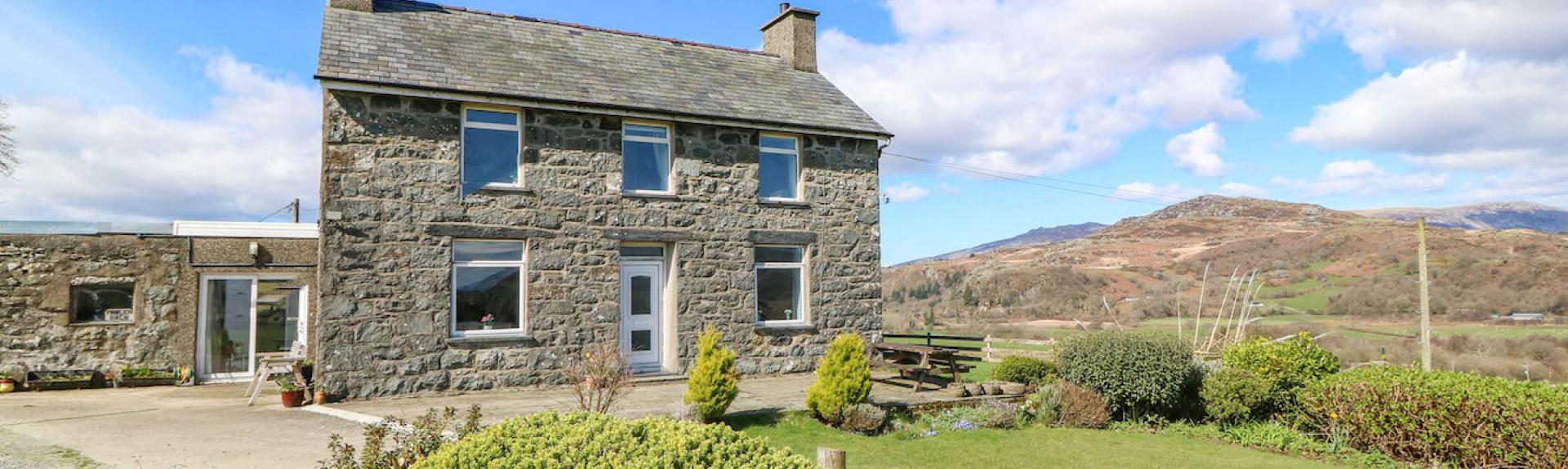 A detached, doubled-froted stone-built house with a slate roof with a slate roof, large lawned garden and views of Snowdonia/