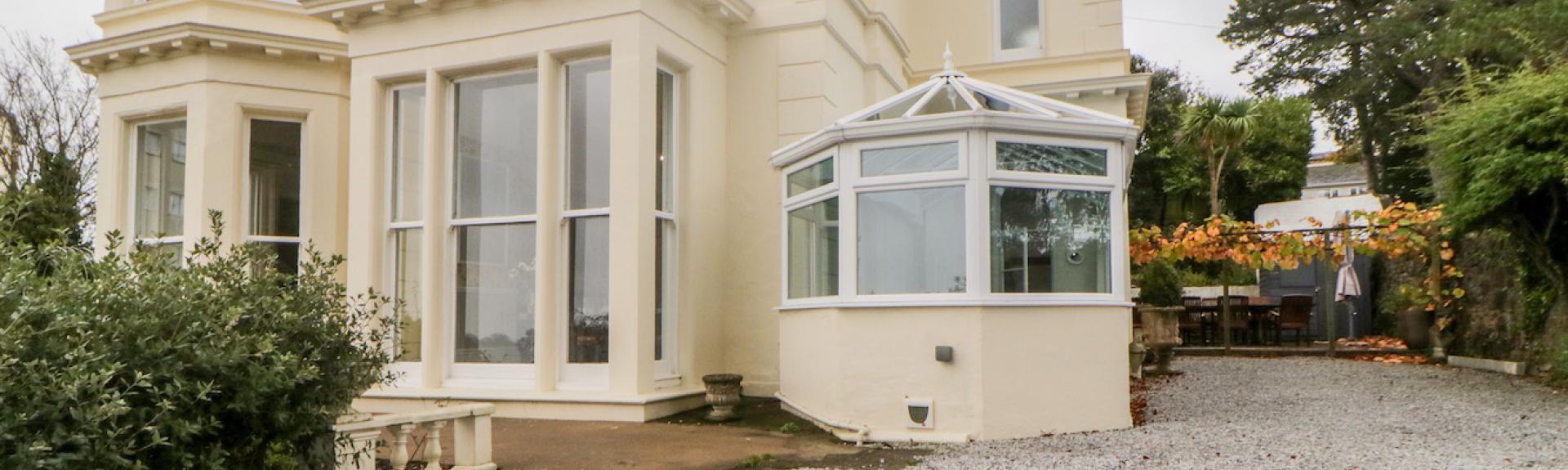 An exterior of s Victorian holiday villa in Torquay with ample car parking space in front.