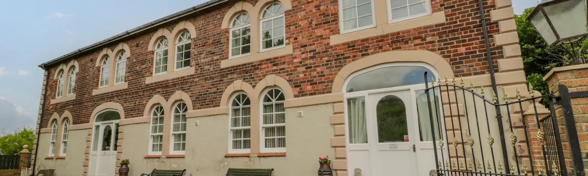 Exterior of The Old Power House converted to a large, 2-storey holiday cottage with two rows of five double windows.
