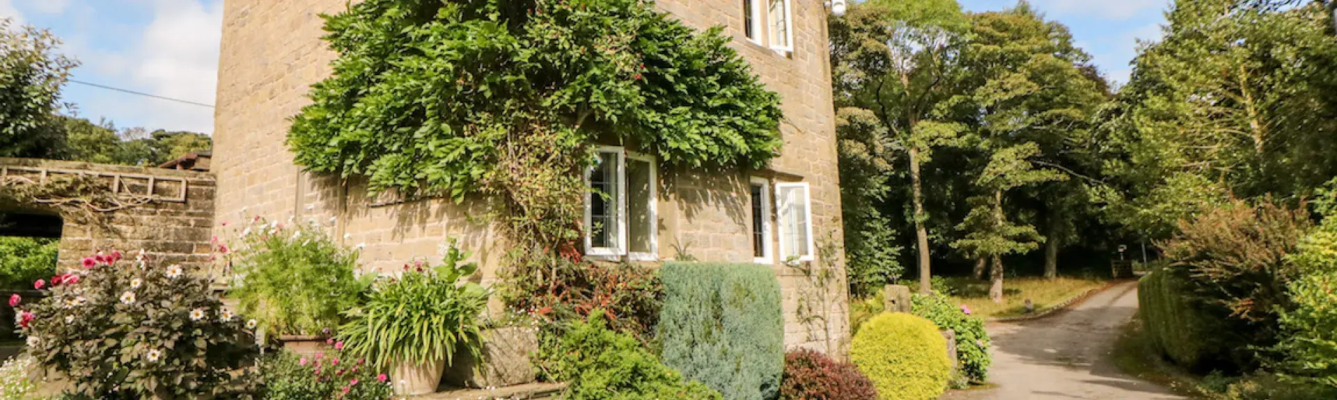 Gable end of a 2-storey pennine holiday cottage overlooking a country lane