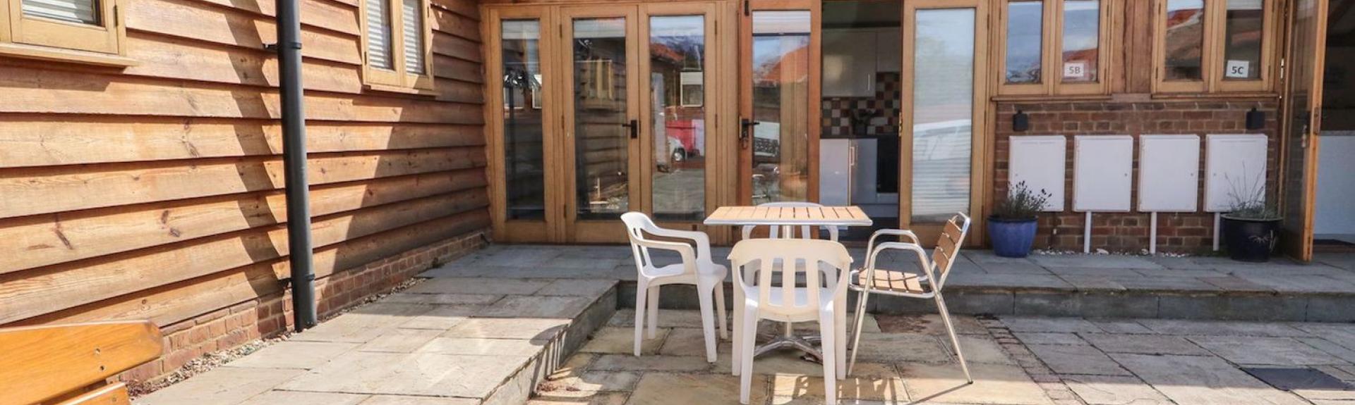 Exterior of a Hunstanton holiday cottage ovrlooking a paved courtyard with outdoor dining furniture