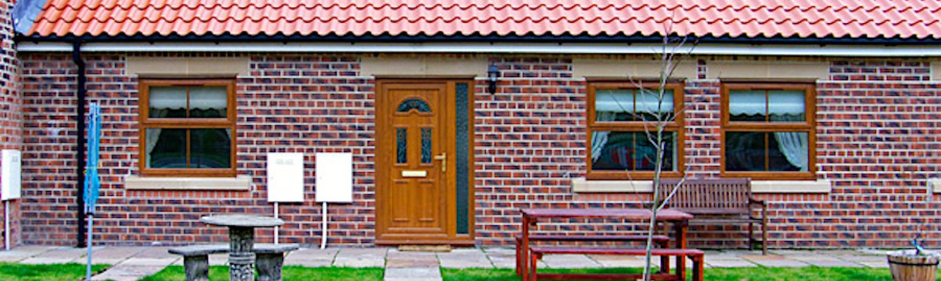 A paved footpath leads to the fron tdoor of a single-storey, brick-built Skinningrove holiday cottage