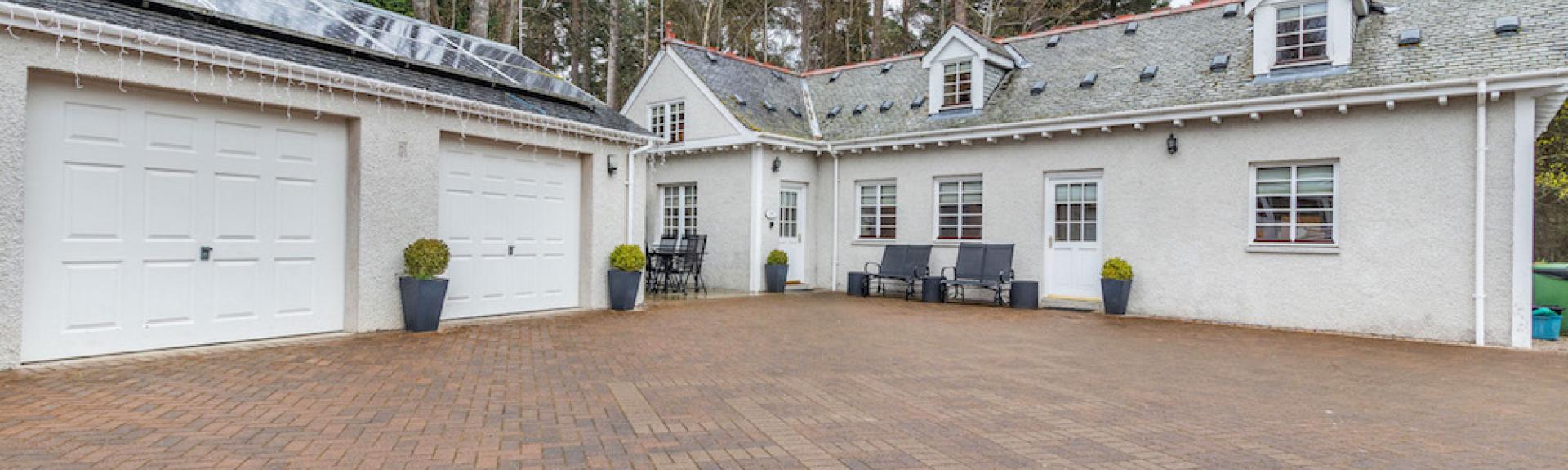 A large inverness-shire holiday cottages and two double garages surround a large block-paved courtyard.