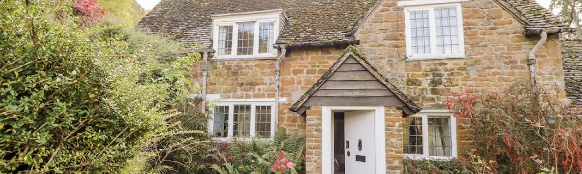 2-storey stone-built Cotswold Cottage surrounded by a mature garden.