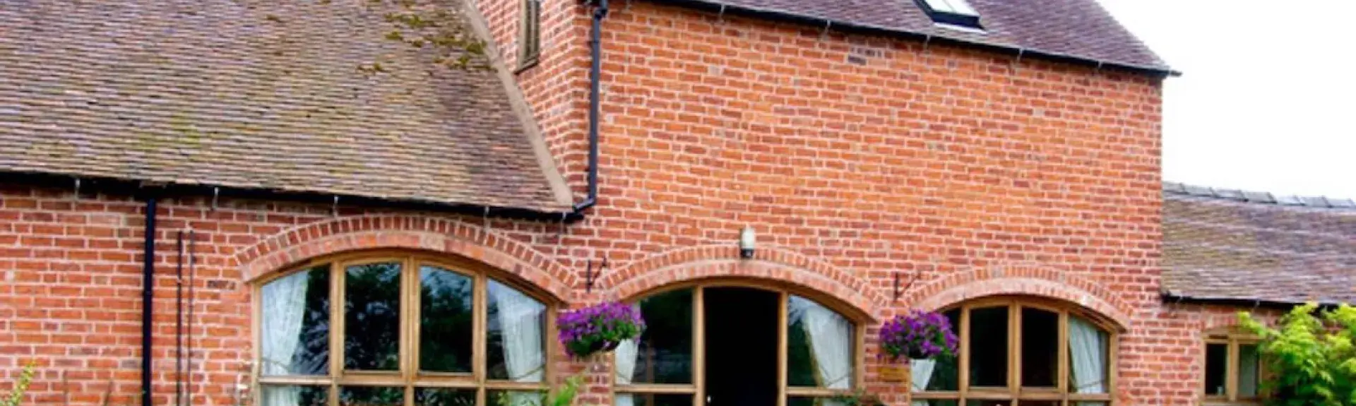 A two-storey Shropshire barn conversion with arched floor-to-ceiling ground floor windows.