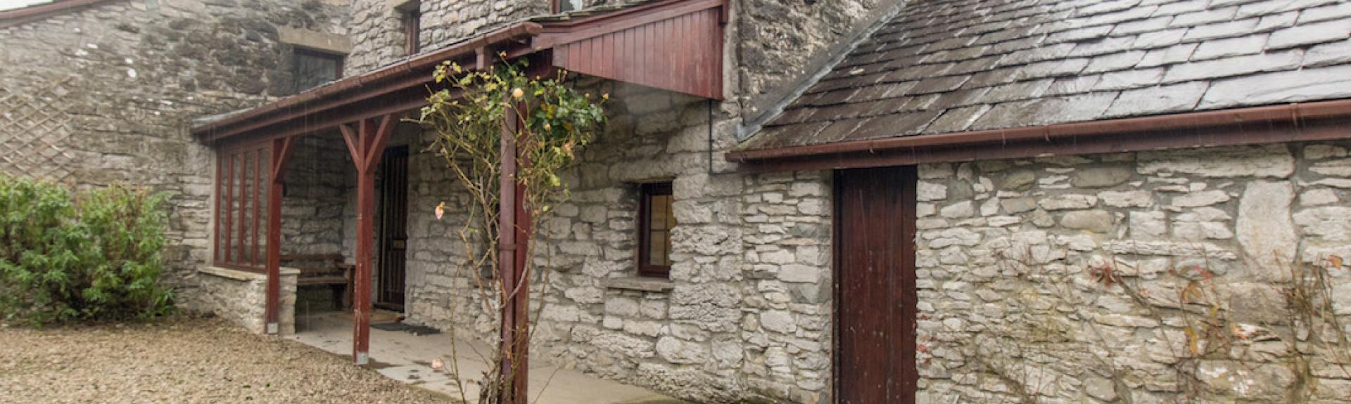 A stone, Cumbrian barn conversion in with a sheltered terrace overlooks a large parking space.