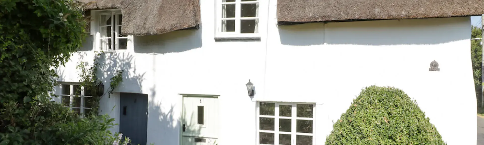 A thatched holiday cottage in Kilve overlooks a shrub-filled garden on the Somerset coast.