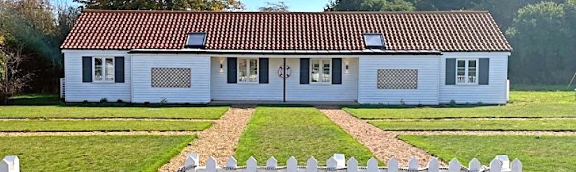 A single-storey holiday cottage on Osea Island overlooks a large lawn.