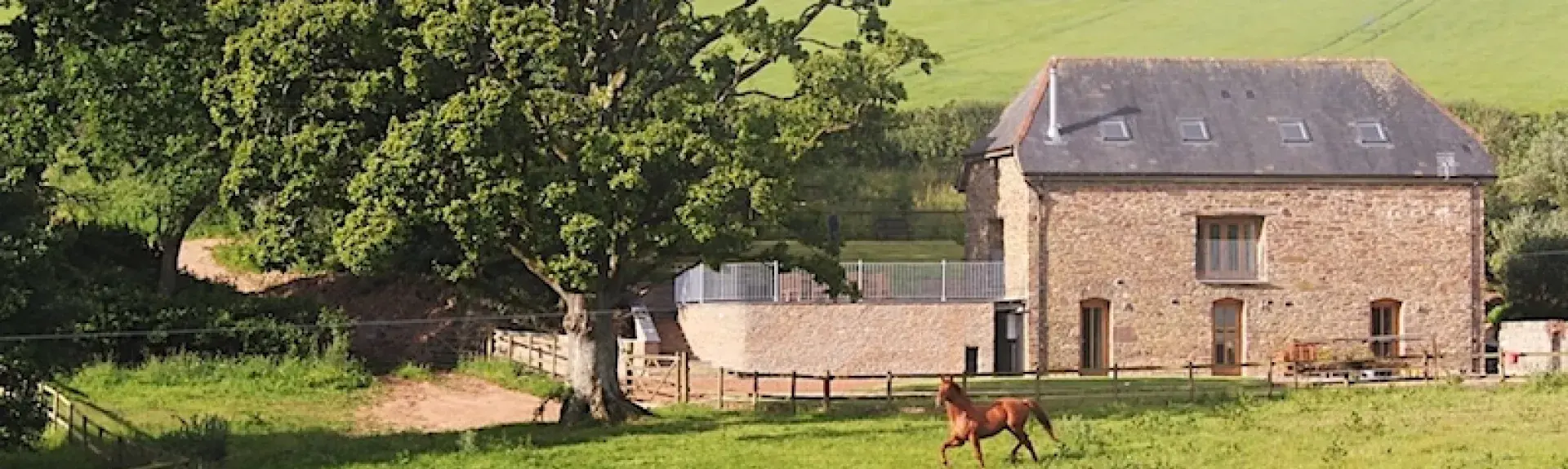 A large large stone barn conversion in Devon surrounded by open fields and mature trees