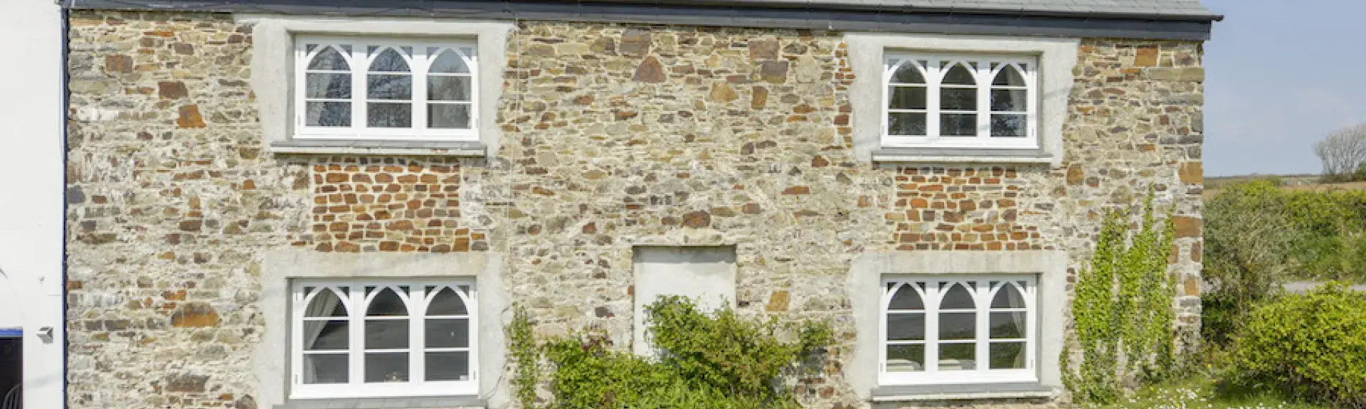 A double fronted stone-built North Devon country cottage with arched windows