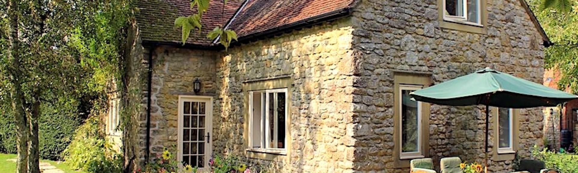 Stone-built Dorset farm cottage with a patio, lawns and mature trees.