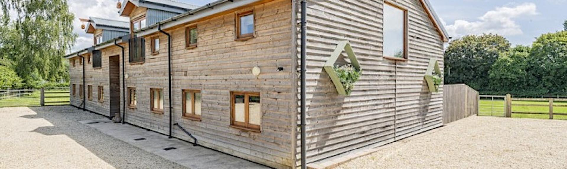 Exterior of a contemporary wood-clad barn conversion comprising 3 New Forest holiday cottages