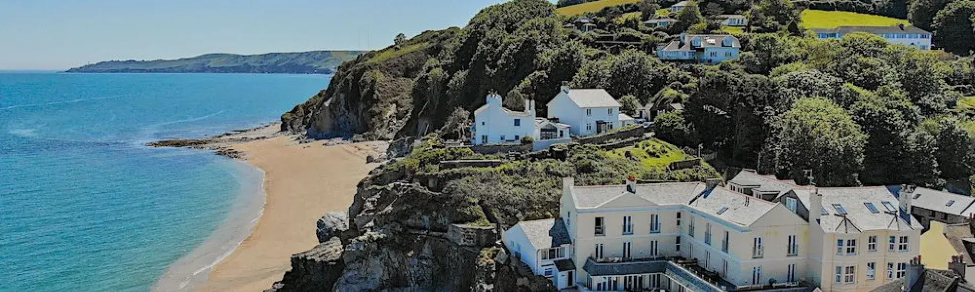 aerial view or a beach with a small seaside village overlooking the sands