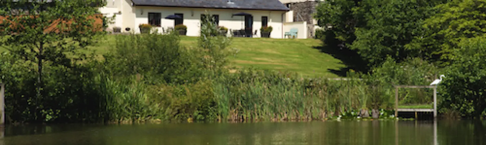 Barn conversions are reflected in the waters of a lake.