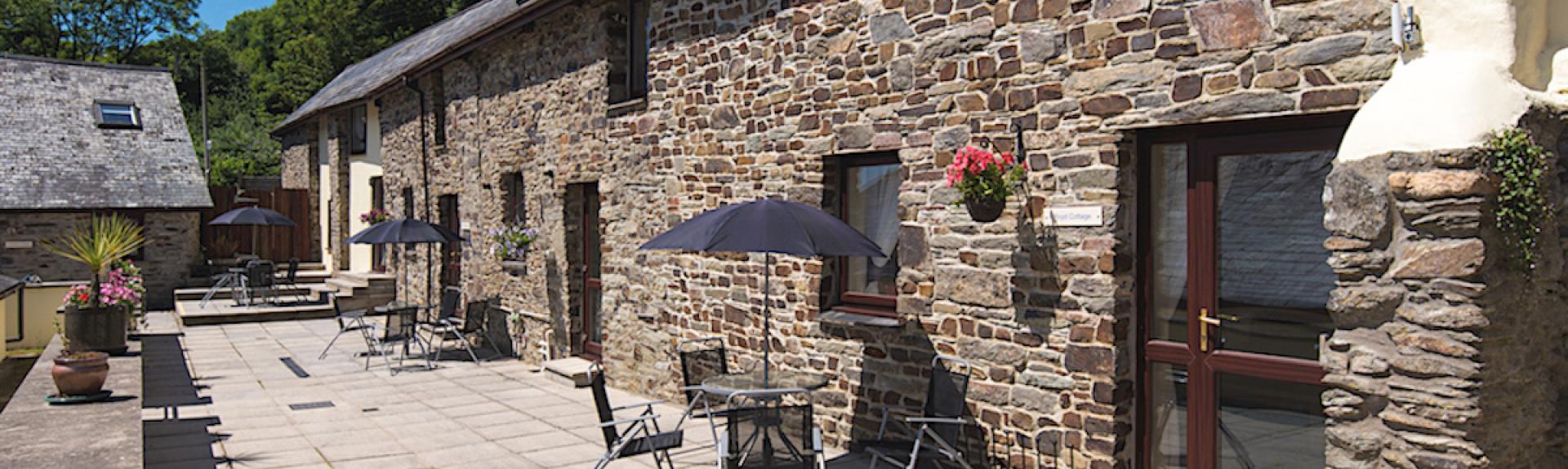 A stone-built barn conversion overlooks a patio with dining table.