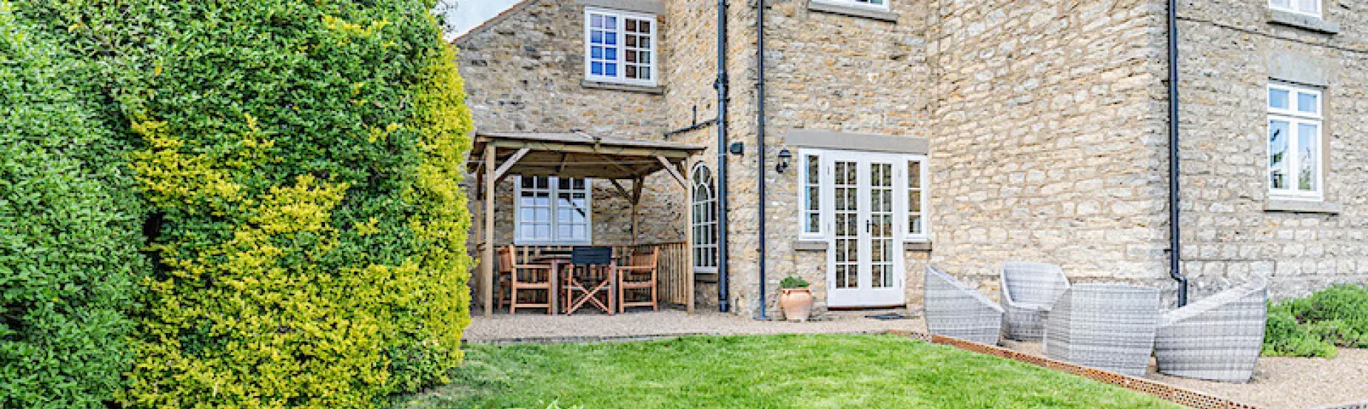 A stoine-built cottage overlooks a large lawn.