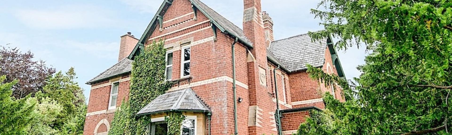 Brick-built Victorian vicarage surrounded by a tree-lined garden.