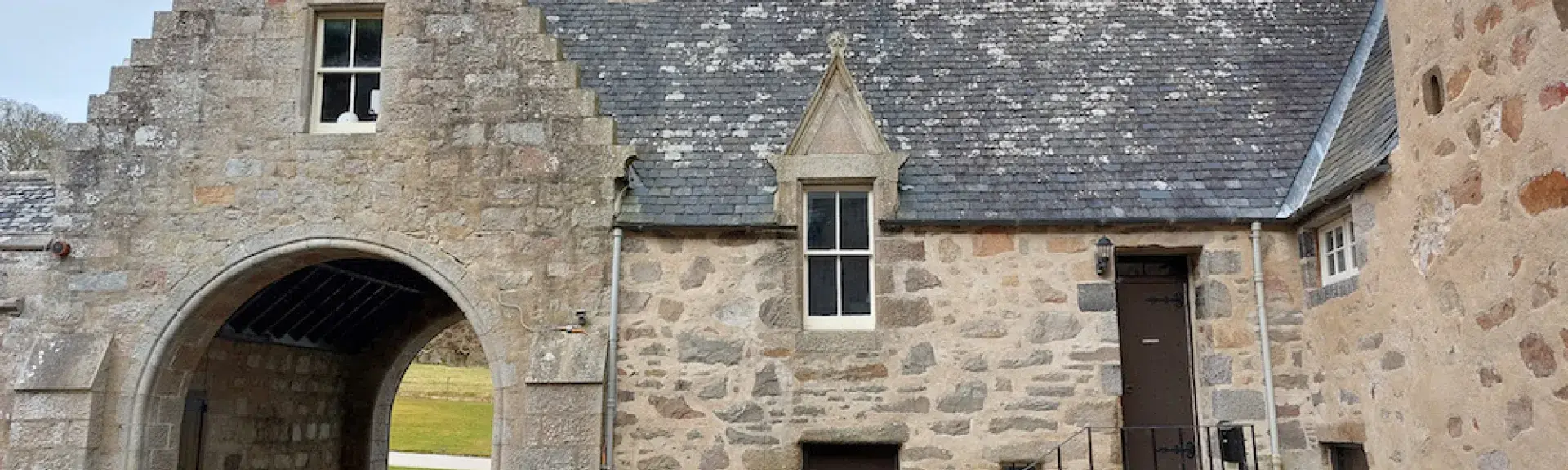 Entry arch and adjoining granite-built cottage overlook a castle courtyard. 